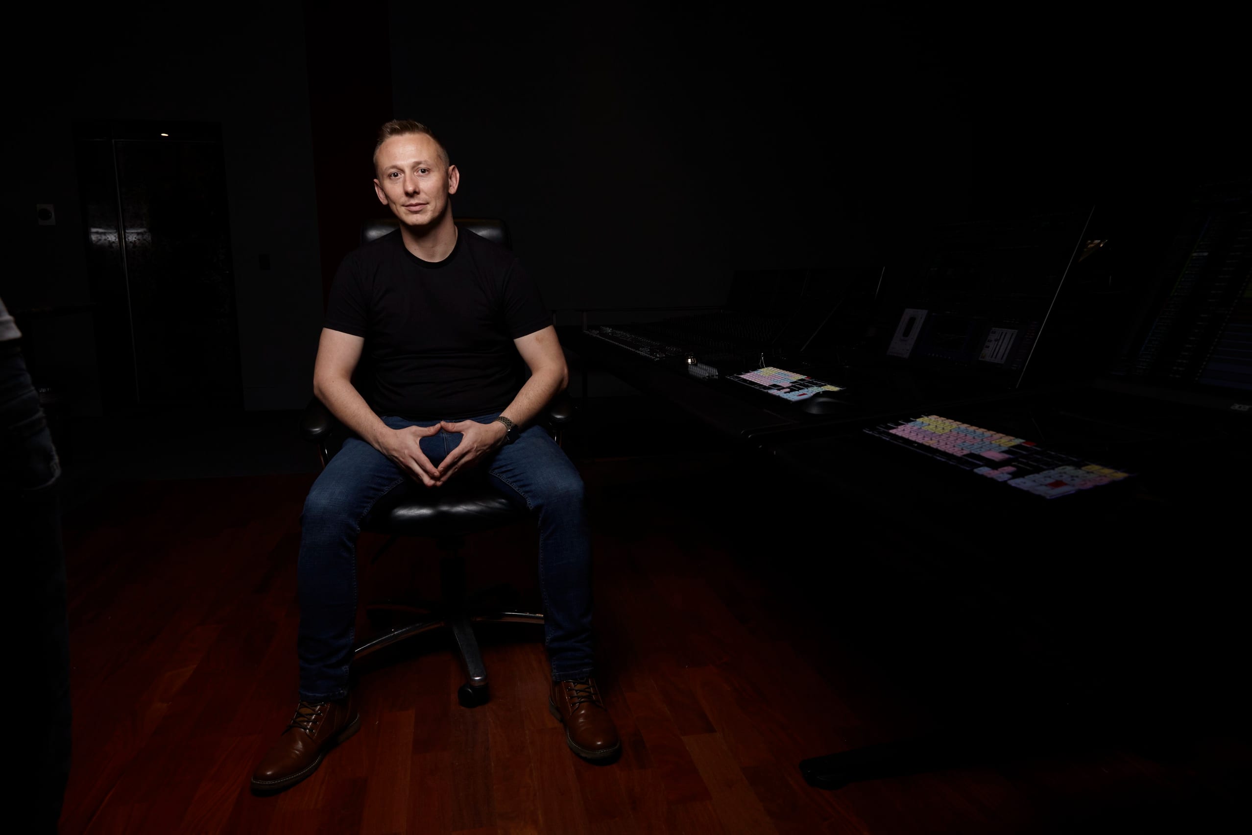 Jason Abell seated in the middle of a darkened dub stage, the mixing console and monitors off to one side.